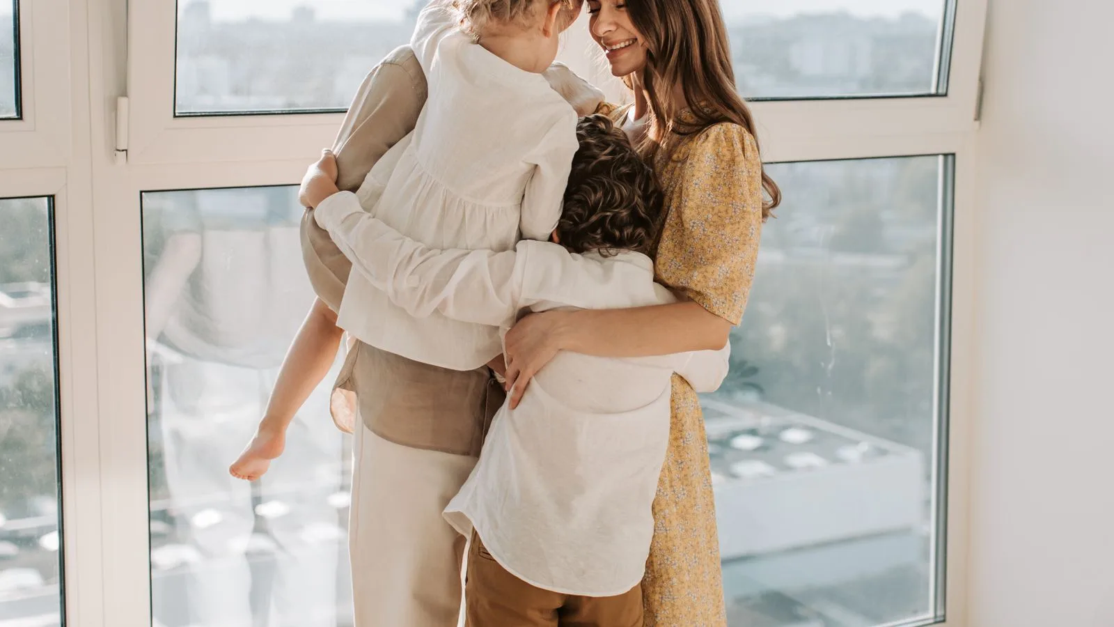 Family sharing a warm group hug in the sunlight at home