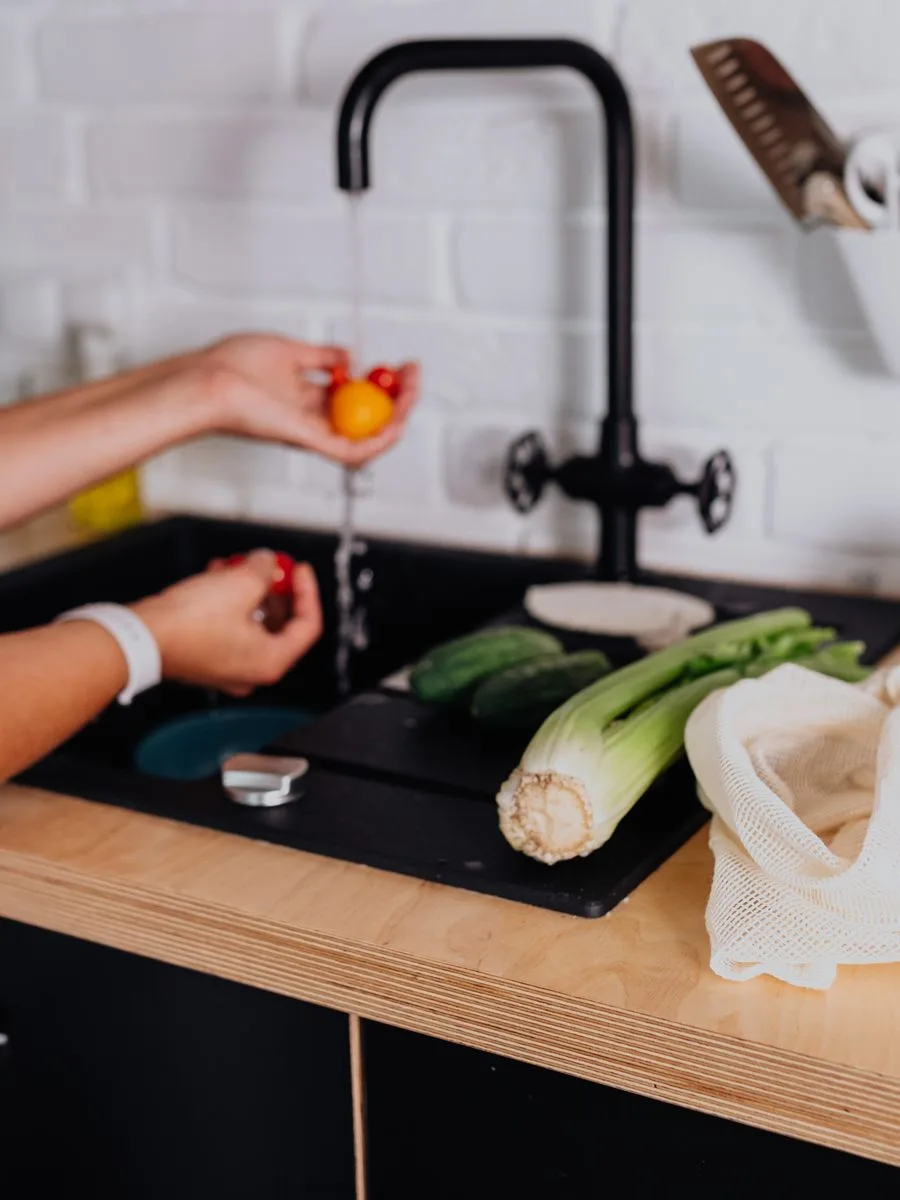 Woman washing fresh vegetables at her kitchen sink