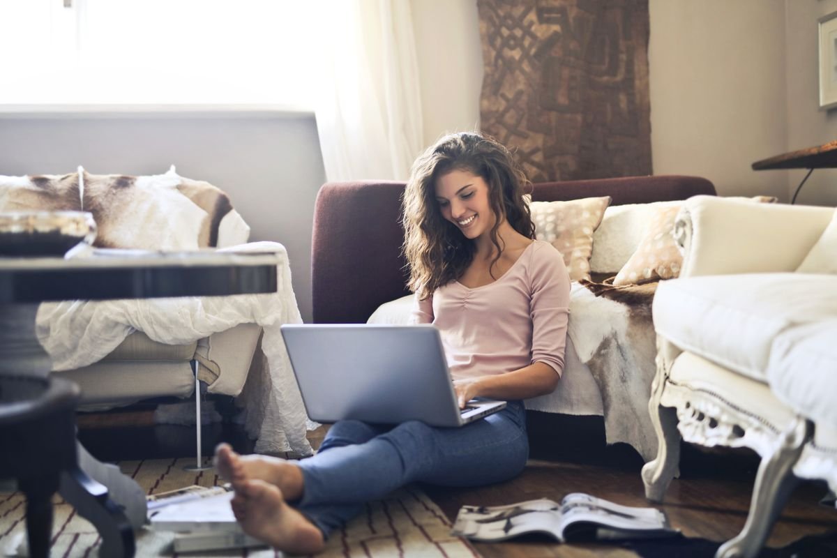 A woman smiling while using her laptop at home